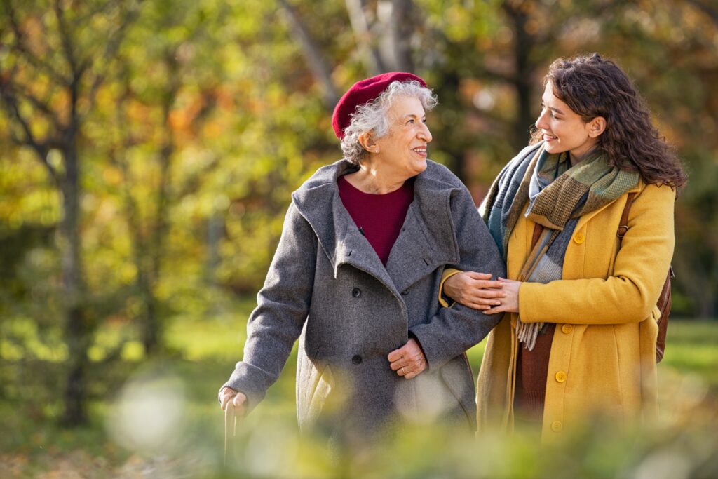 Elderly woman walking outside with younger woman